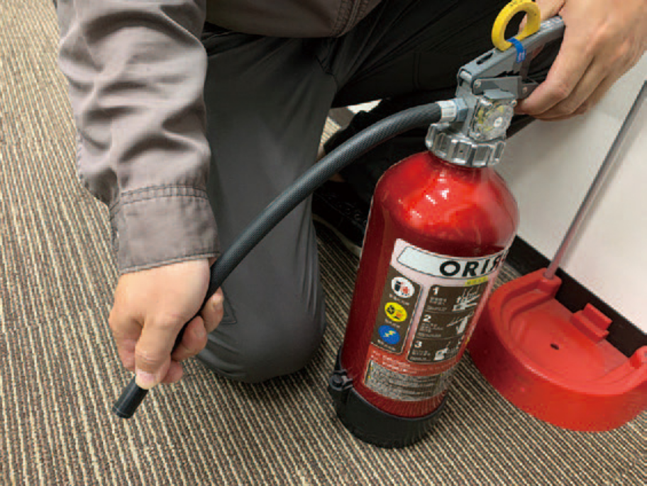 作業員が消火器のホースを確認している点検作業の様子